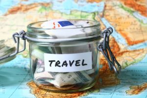 Travel budget - vacation money savings in a glass jar on world map
