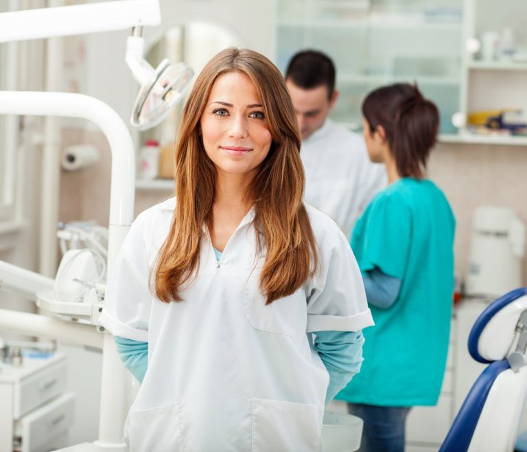 Dentist smiling with other dentist in background