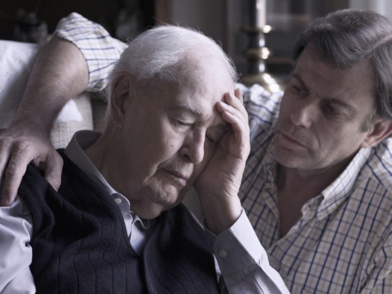 Portrait of an elderly man, comforted by his son