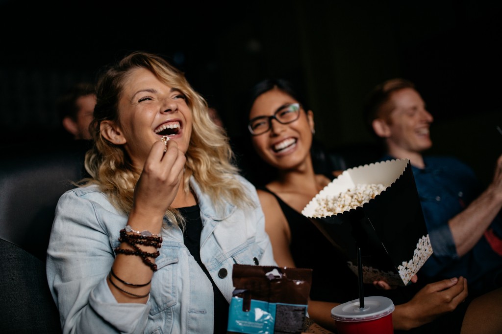 Friends watching a movie while eating popcorn