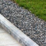 curb of the house with gravel beside the grass
