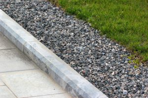 curb of the house with gravel beside the grass
