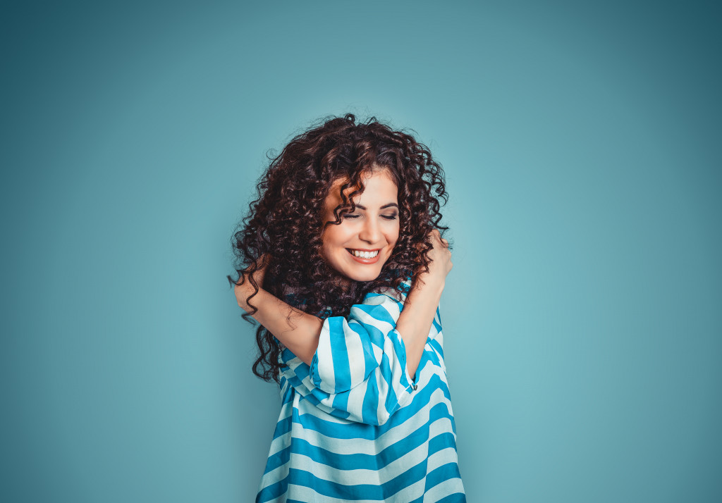 curly haired woman hugging herself