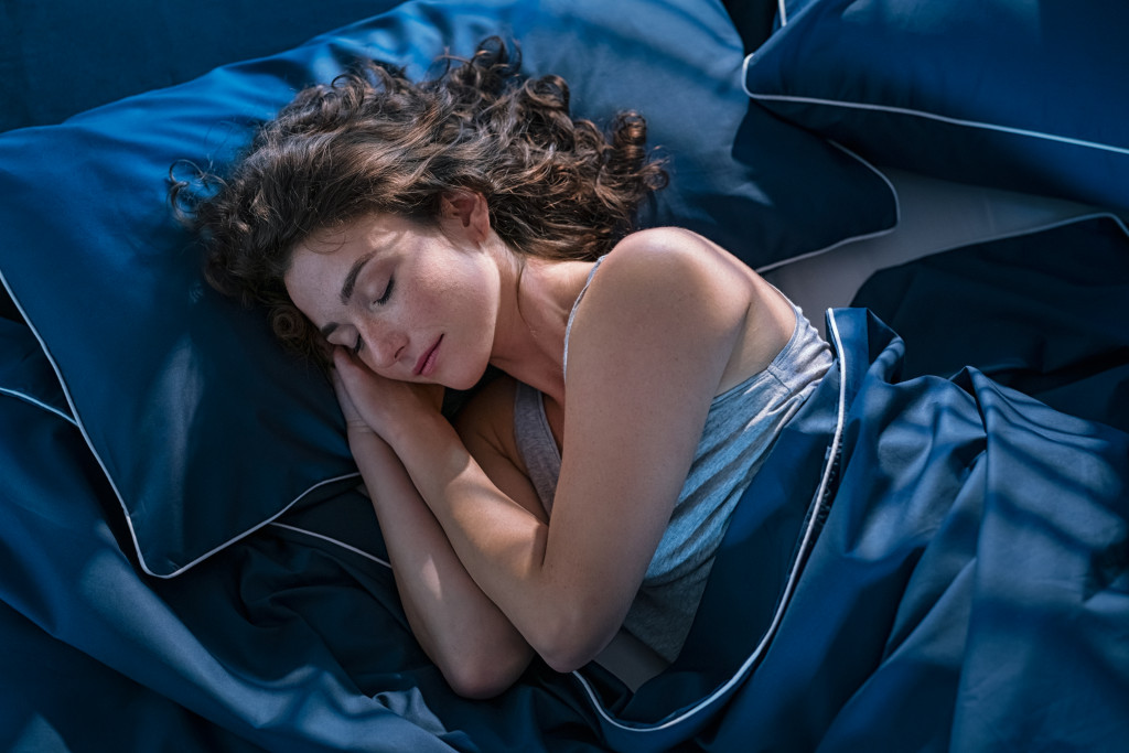 A beautiful woman sleeping on a blue satin bed